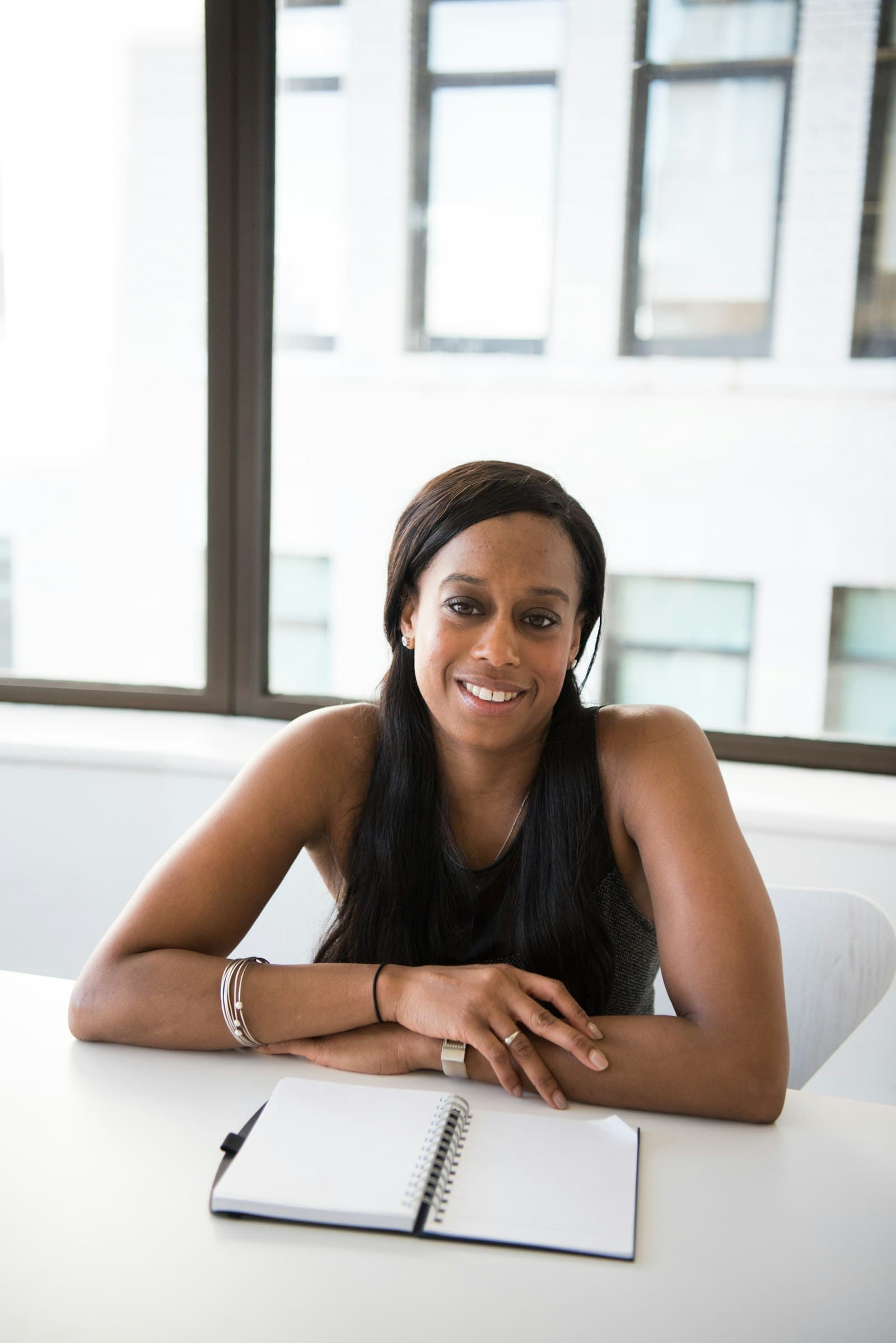A smiling business owner at her desk with a notebook.