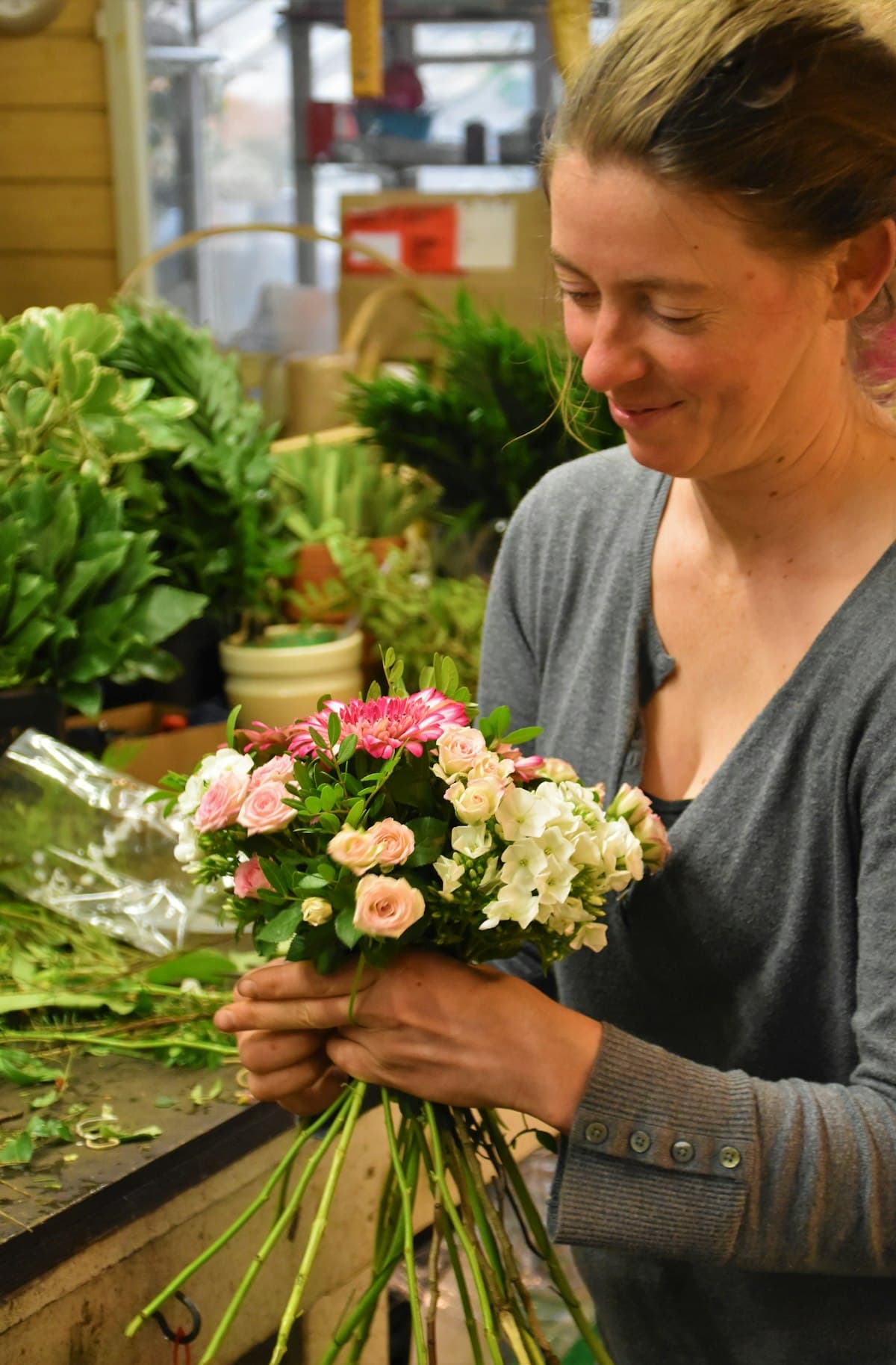 A florist smiling as she wraps a bouquet.