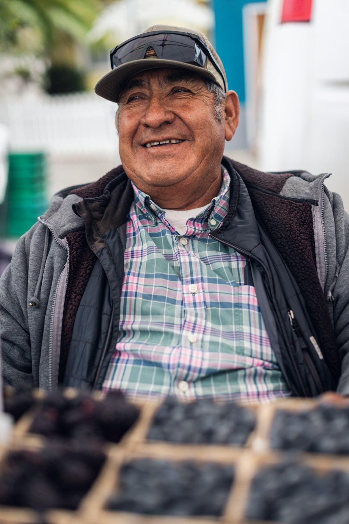 A market vendor laughing behind his crates of berries.