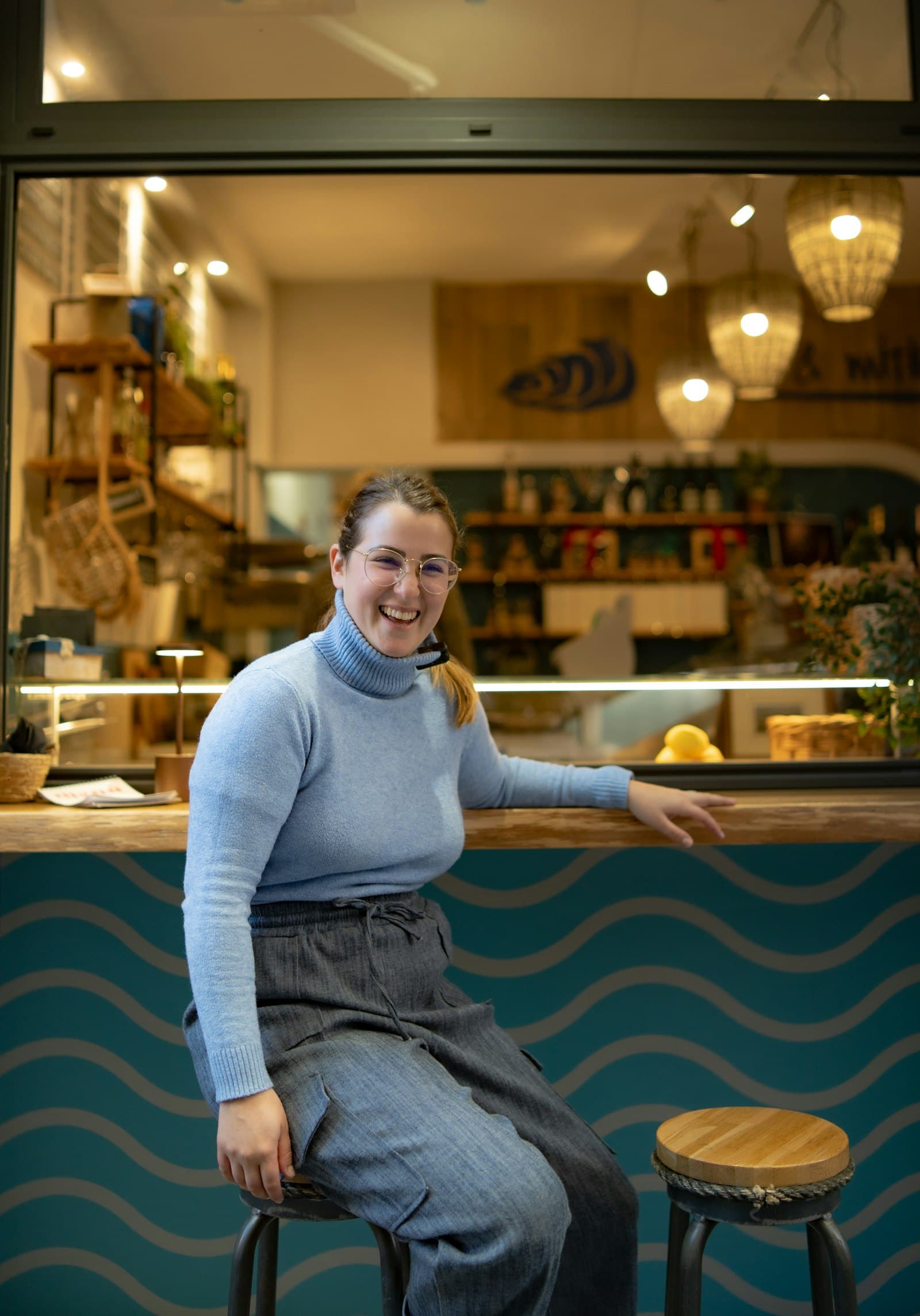 A smiling café owner sitting at the counter of her café.