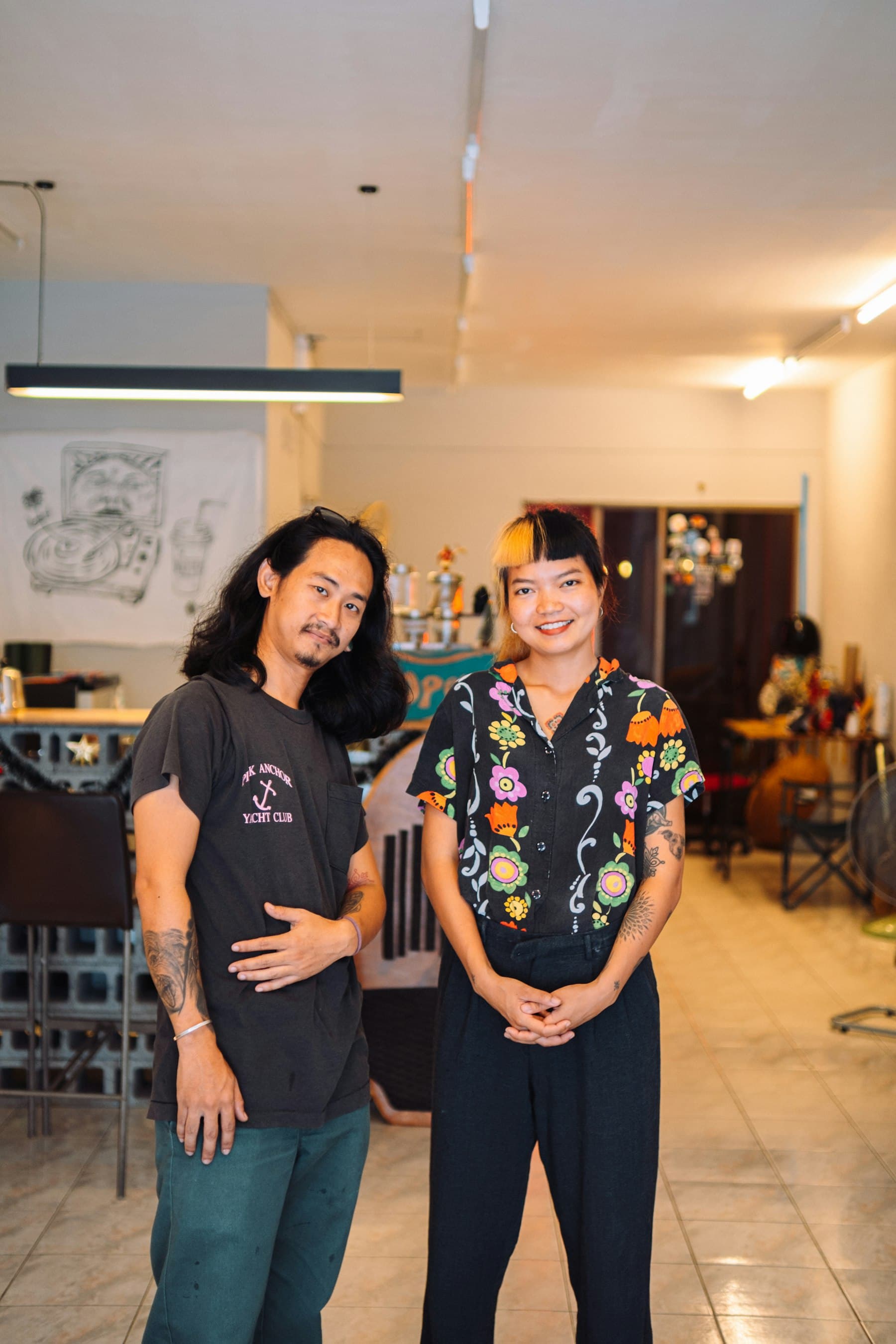 Two owners standing together, smiling, inside their shop.