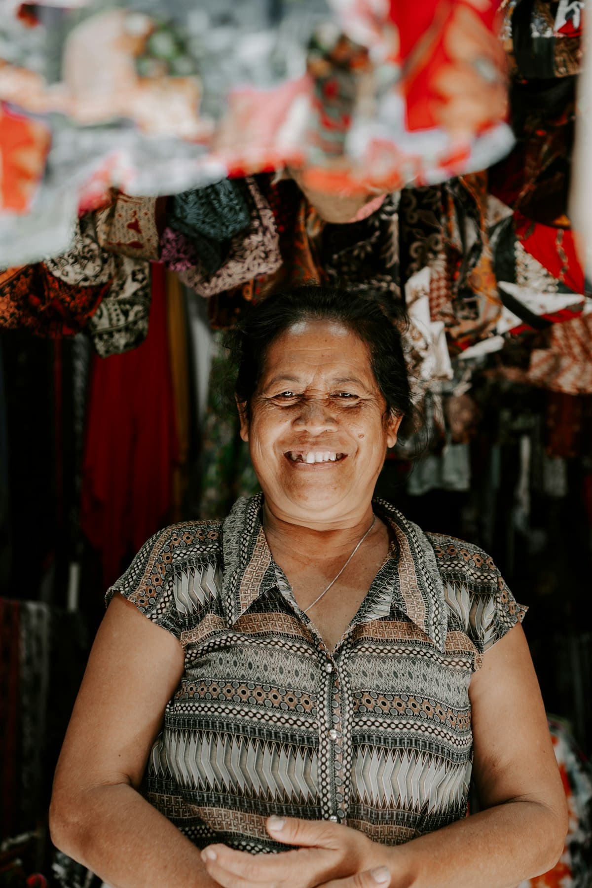 A fabric-shop owner smiling among her bolts of cloth.